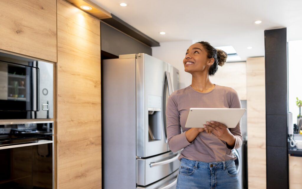 Happy woman controlling the lights of her smart house using an automated system from a tablet computer