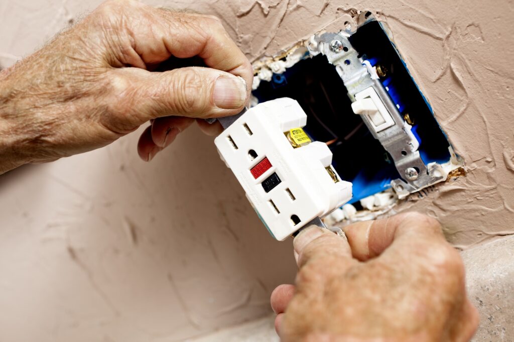 Electrician installing GFI plug in kitchen.